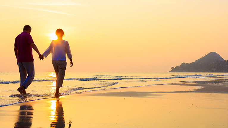 Couple walking on beach watching sunset